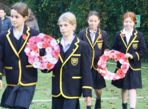 Children lay handmade wreaths at remembrance service in school grounds