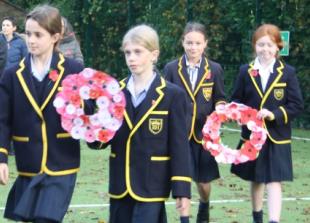 Children lay handmade wreaths at remembrance service in school grounds
