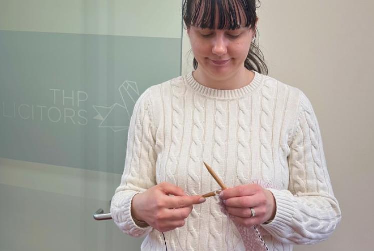 Woman knitting for charity in memory of footballer